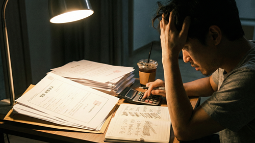 늦은 밤까지 스탠드 불빛 아래서 개인회생 보정권고 서류를 보며 월 변제금을 계산하고 고민하는 모습